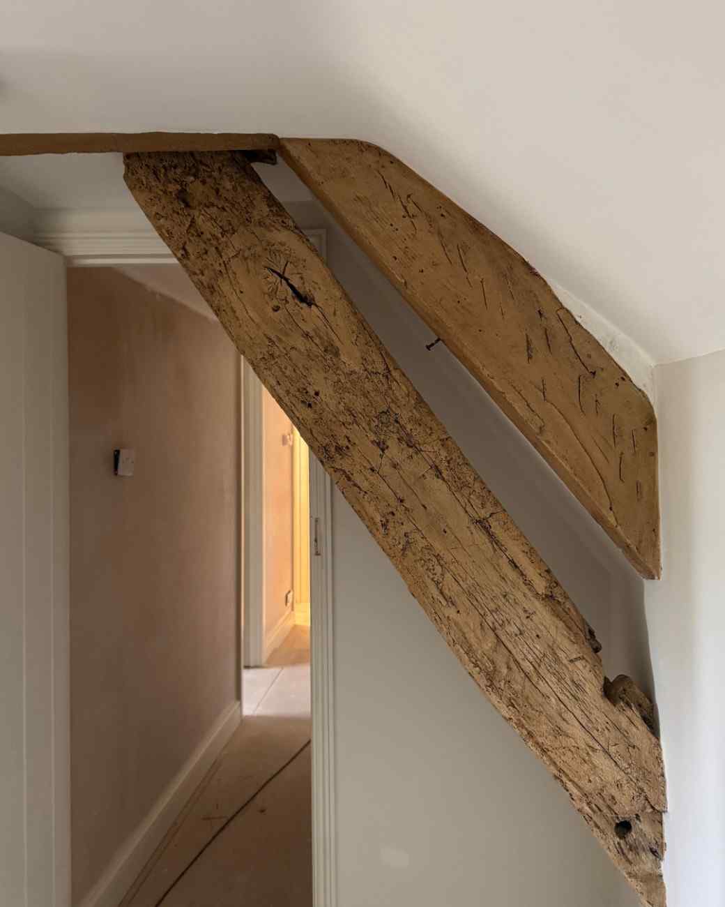 A raking ceiling beam over a landing after restoration, in a warm honey oak
